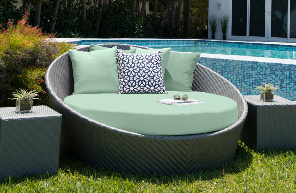Pale green daybed on lawn in front of pool.