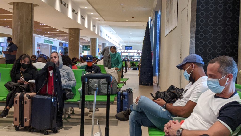 Travelers choose to distance themselves from others in the PUJ Airport departures lounge.