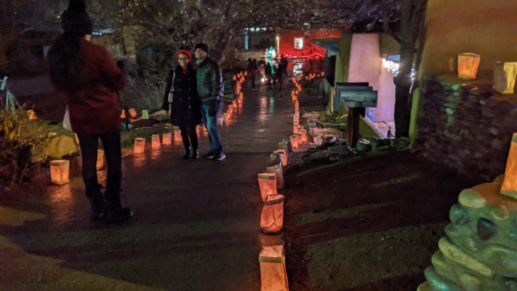 Couple poses for a picture in front of the farolitos that are lit on Christmas Eve along Canyon Road in Santa Fe.