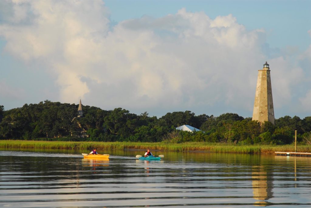 Old Baldy Lighthouse watches over kayakers exploring the shores of Bald Head Island. Photo c. BaldHeadIsland.com