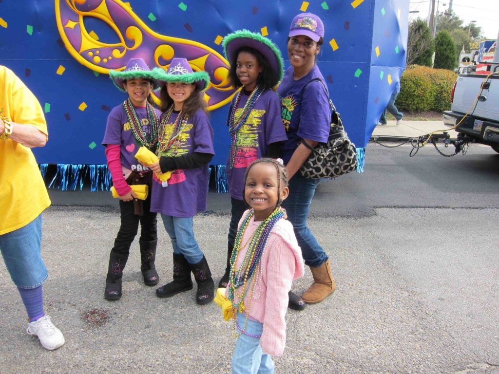 Family in Mardi Gras outfits at Biloxi Mississippi Mardi Gras parade.