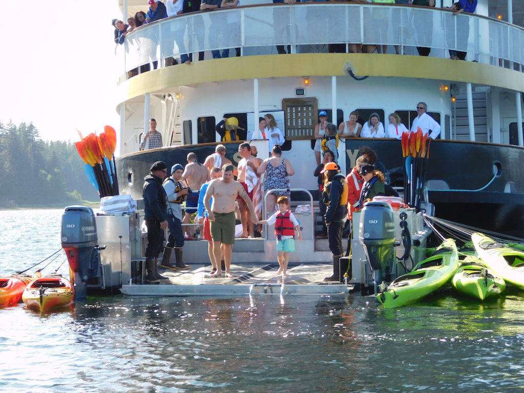 Father and son jump into Alaska's cold water from the back deck of an UnCruise ship on an Alaska family adventure. Photo. c. UnCruise Adventures