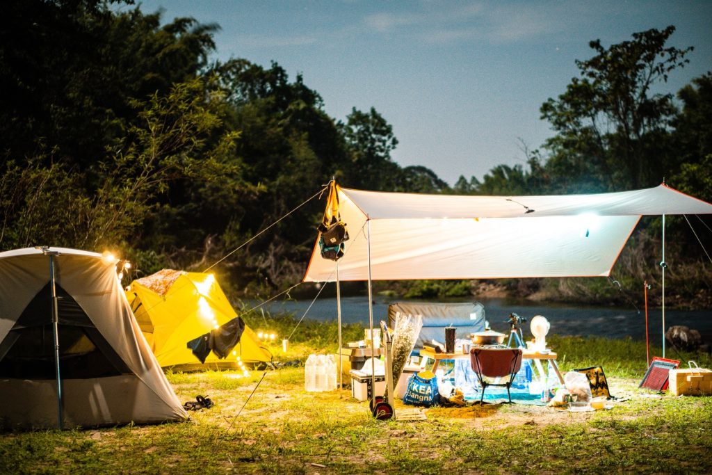 Tarp set up over dining area outside two tents at campsite.