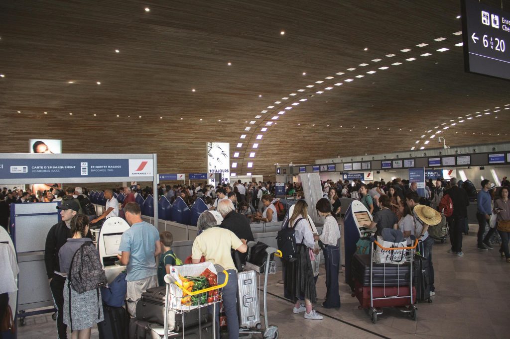 Crowded airport terminal where families are checking in for flights. Photo by Connor Danylenko for pexels.