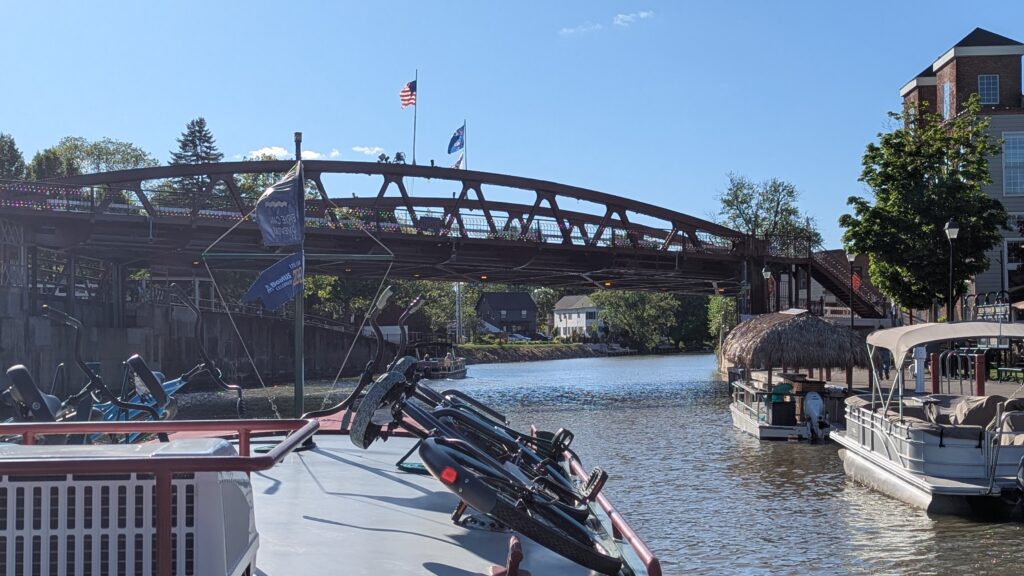 Rental housboat with bikes on top approaches a lift bridge at Fairport, New York on the Erie Canal.