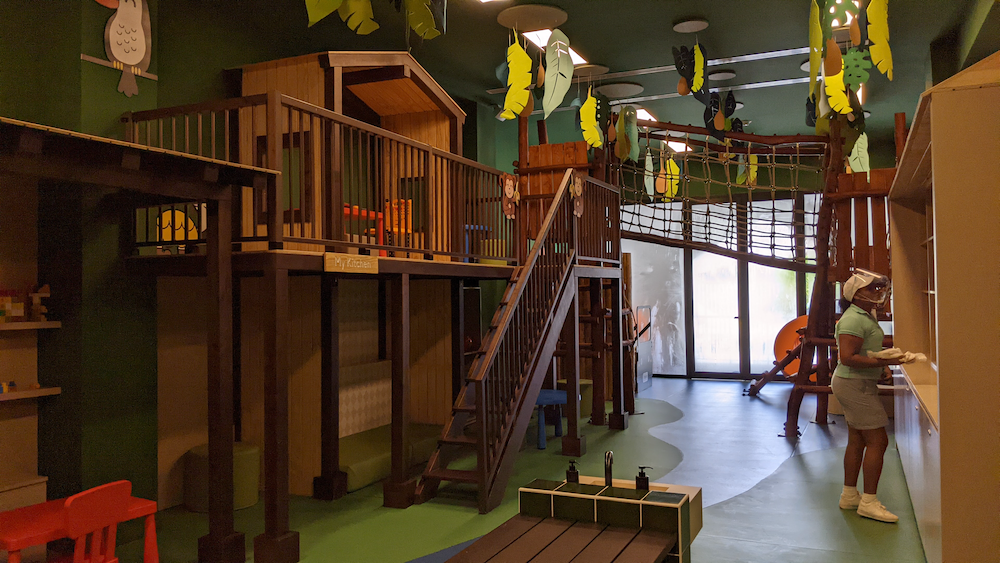 Kids club supervisor organizes the forest-themed childrens playroom for the day.