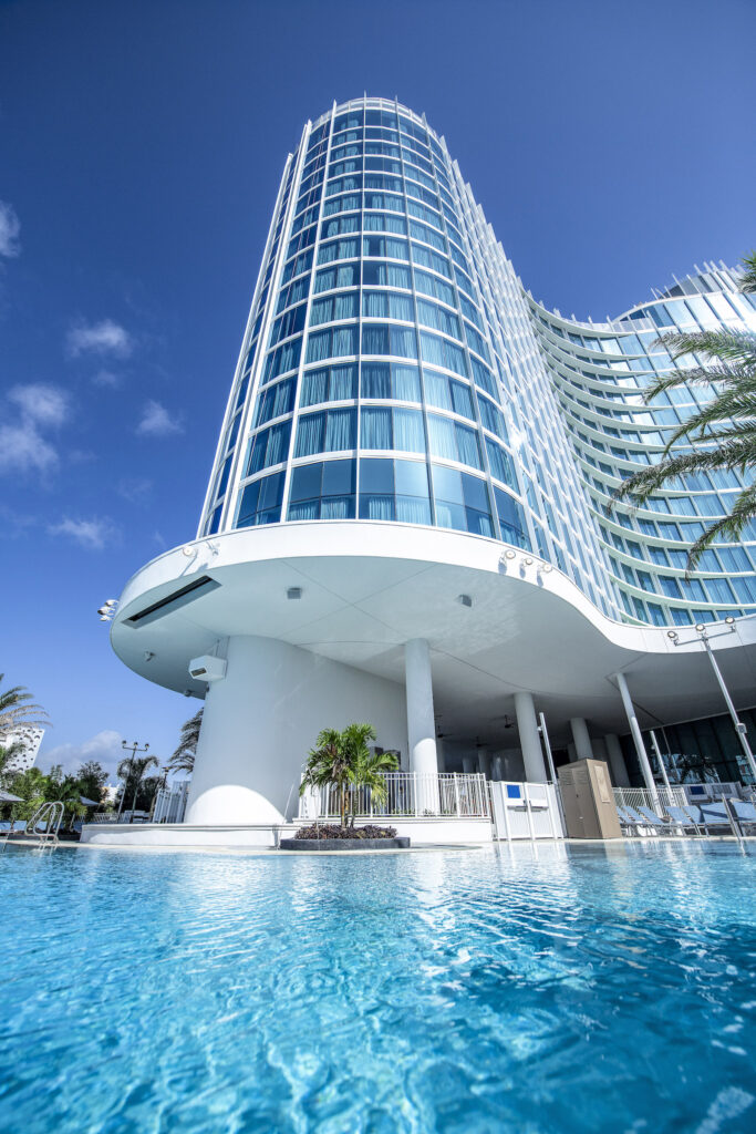 Refelctive blue glass exterior of Universal Aventura Hotel and its pool, one of the top budget family suites at Universal. Photo c. Universal Orlando Resort