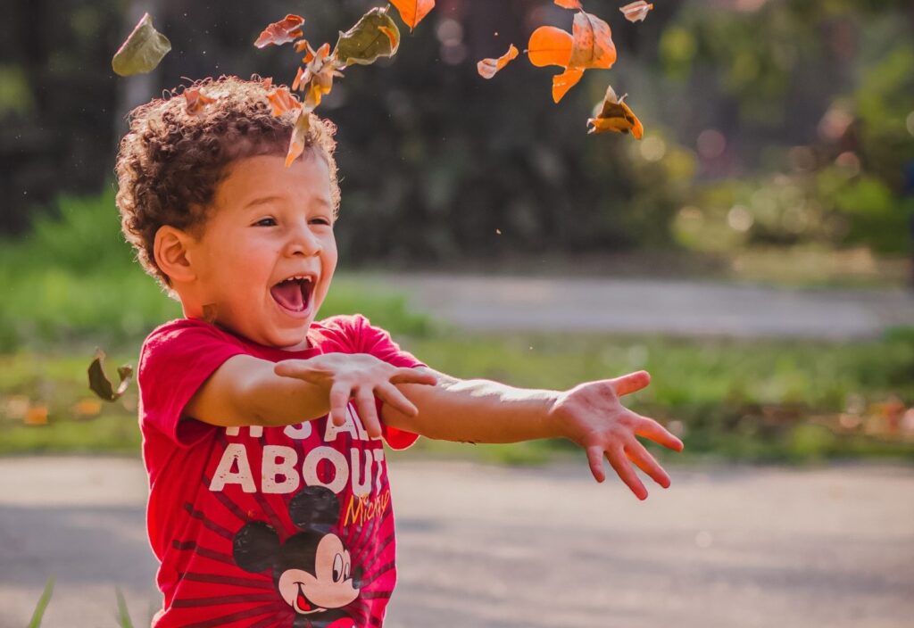 Boy enjoying throwing leaves on a fall getaway. Photo c. Gusstavo Santana for pexels