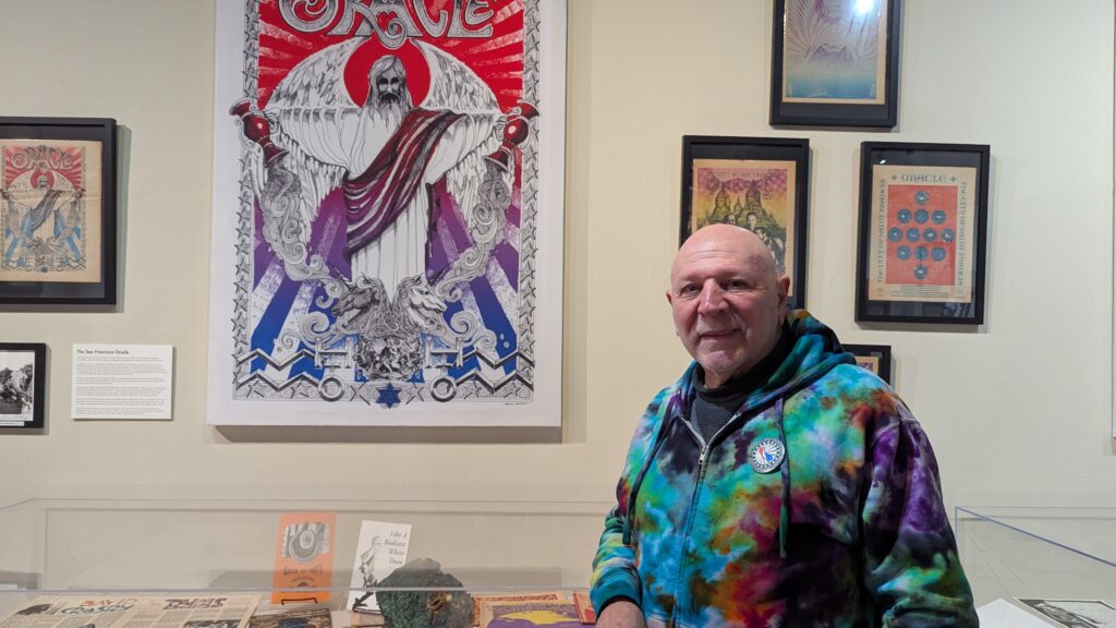 Counterculture Museum owner points out a display of Oracle Magazine posters from the Hippie era.