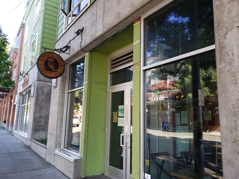 A Circular Wooden Sign Across From Archie Mcphee'S