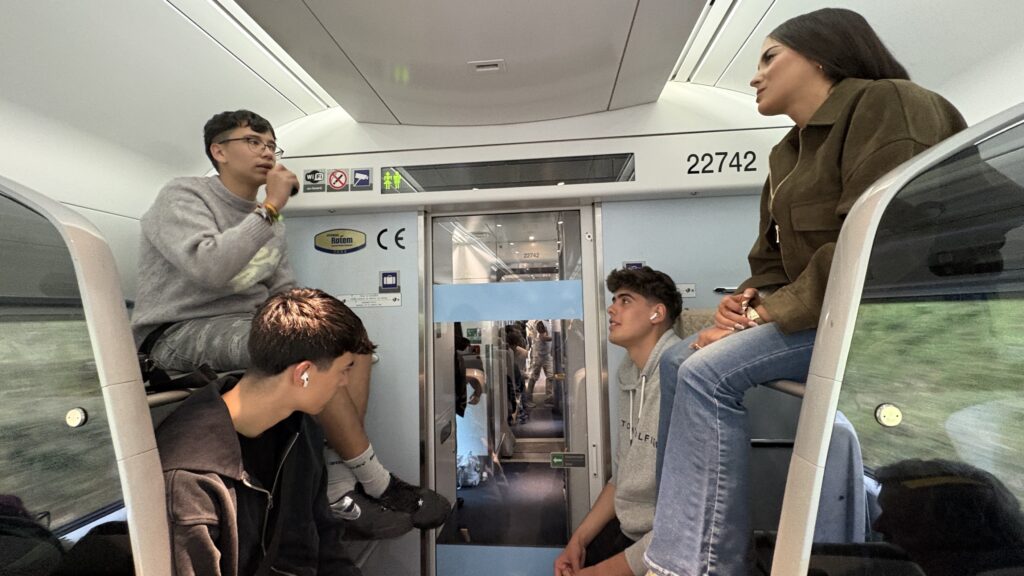 Students without seats climb into luggage racks on Irish train.