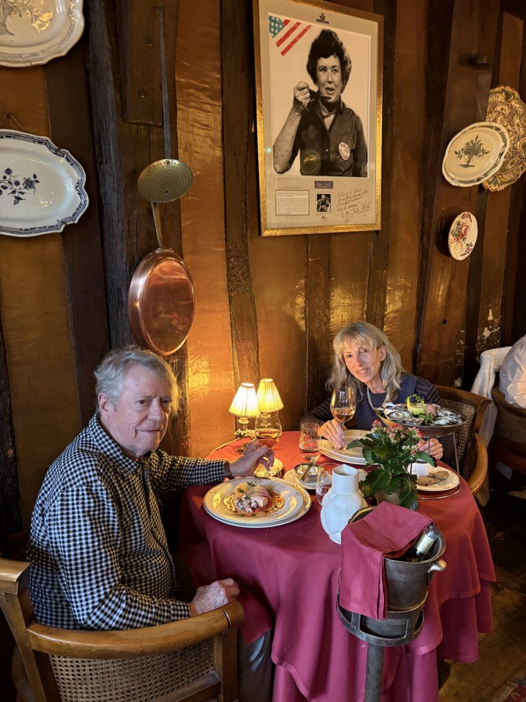 Author and husband seated under Julia Child's portrait at La Couronne in Rouen!